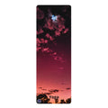 A tall, narrow yoga mat featuring a scenic sunset sky print with pink, red, and dark purple clouds, with the word 'Yoga' printed at the bottom.