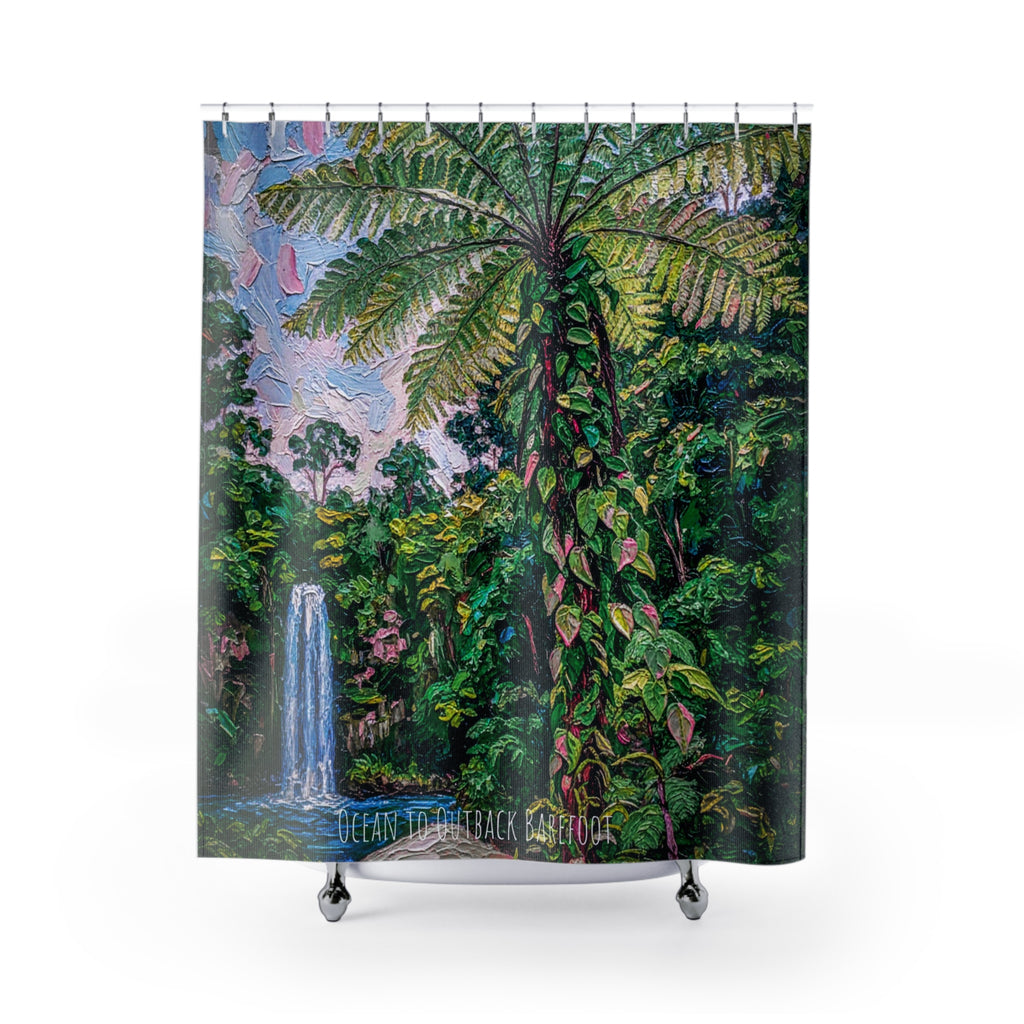 This shower curtain features a waterfall in the background and a lush green king fern in the middle. Hung on a silver shower curtain rod over a bath.