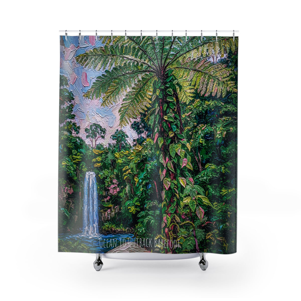 This shower curtain features a waterfall in the background and a lush green king fern in the middle. Hung on a silver shower curtain rod over a bath.