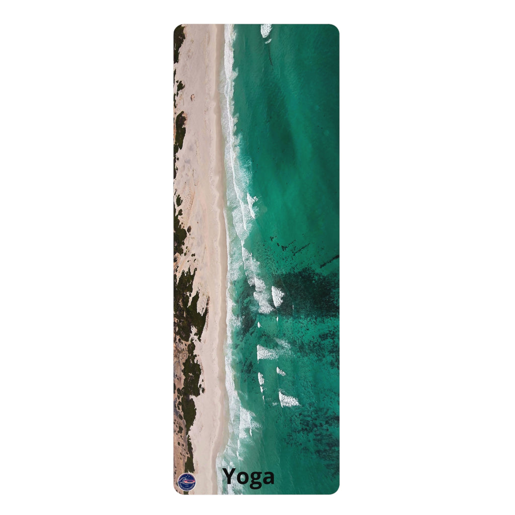 A tall, narrow yoga mat featuring an aerial photograph of a beach and turquoise ocean, with the word 'Yoga' printed at the bottom.