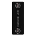 A black rectangular yoga mat with rounded corners, featuring the text 'OCEAN TO OUTBACK BAREFOOT' in white vertical lettering, flanked by two circular logo designs at the top and bottom on a white background.